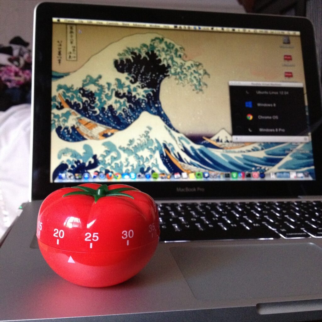 A tomato timer sitting on a MacBook Pro